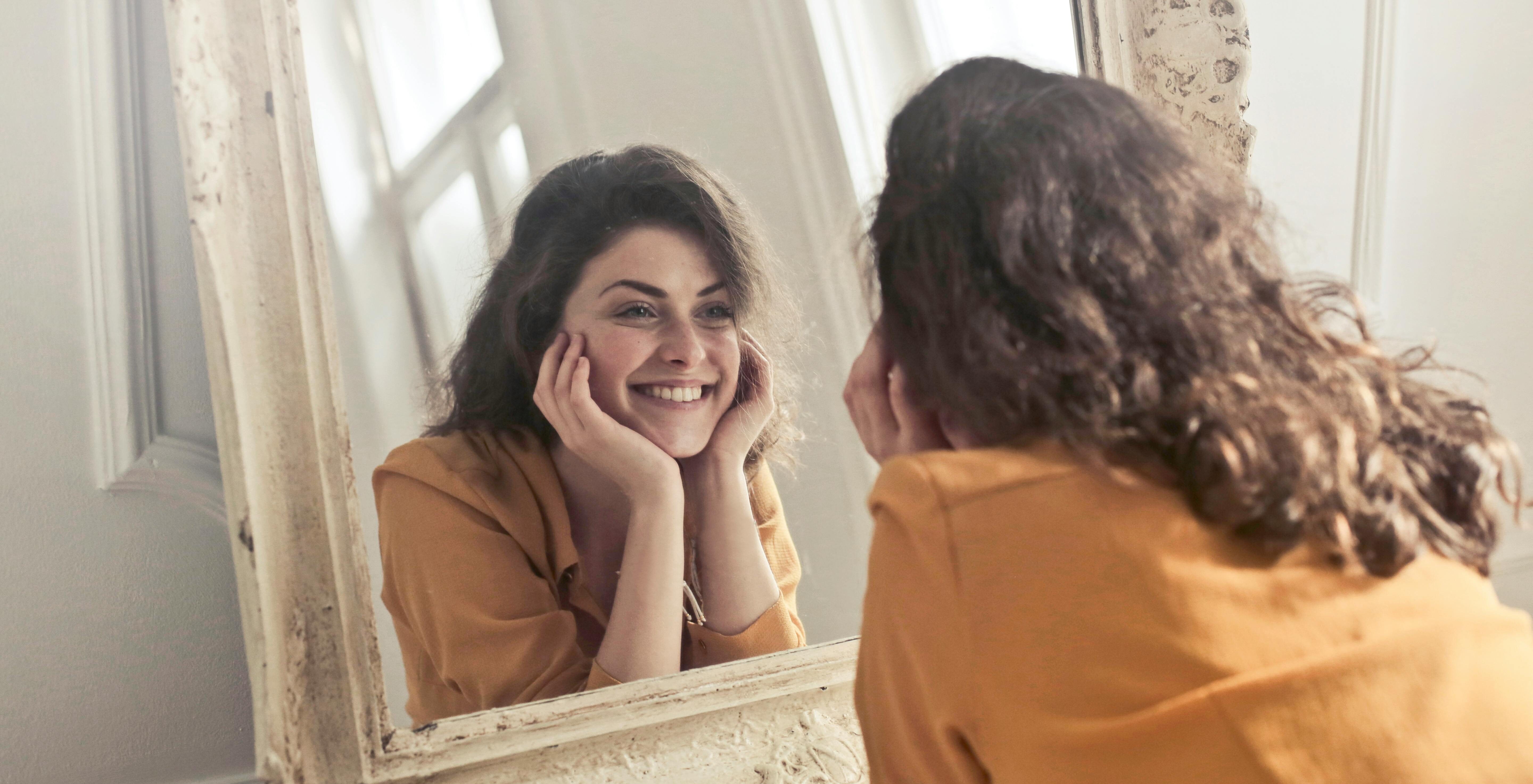 Junge Frau spricht sich im Spiegel Ermutigung zu